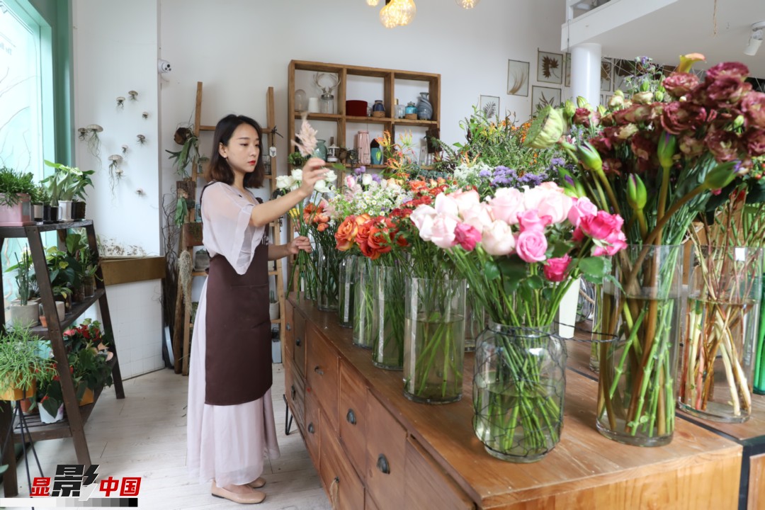 王黎媛是一名河南姑娘，在昆明念完大學后，就再也舍不下春城的藍天陽光、青山碧水，更舍不下這里的四時繁花，于是就干脆留了下來，成了一名媒體人。2017年的時候又毅然辭去工作，創業開起了花店，成了都市里的一名“花房姑娘”。圖為王黎媛在自己的花店中整理鮮花。新華網 周亞平/攝 念新洪/文